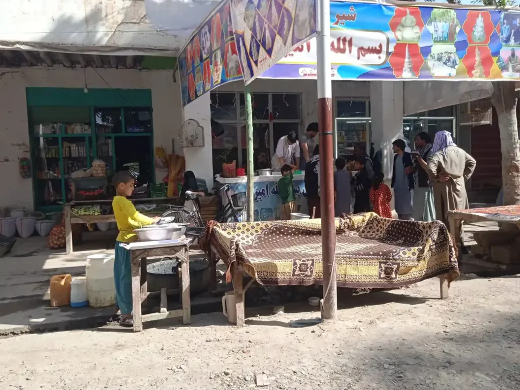 A man making ice cream in Afghanistan and a group of customers around him.